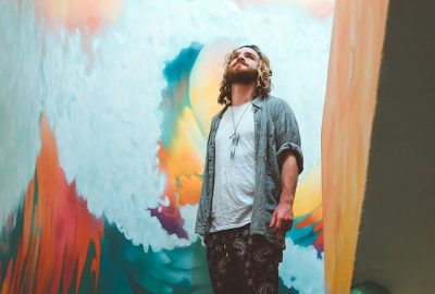 artist looking at the sky while next to a coloured wall on a staircase